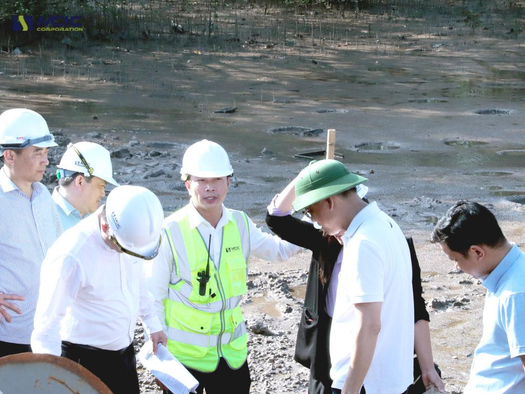 Thứ trưởng cùng đoàn đại diện các Vụ các Cục đứng trên mẫu bùn đã qua xử lý đóng rắn dưới nước sau 21 ngày 